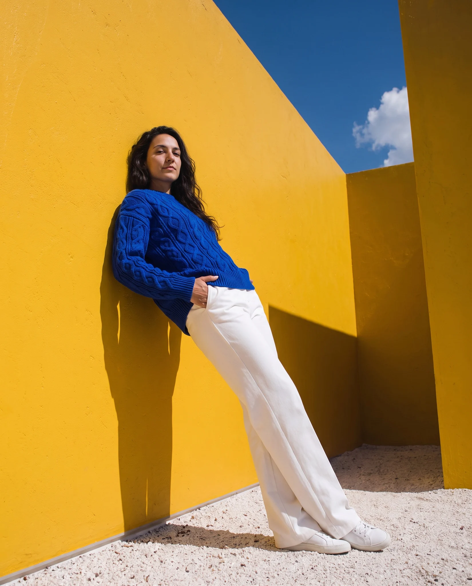 Model in a cobalt cable-knit jumper against sunlit yellow walls